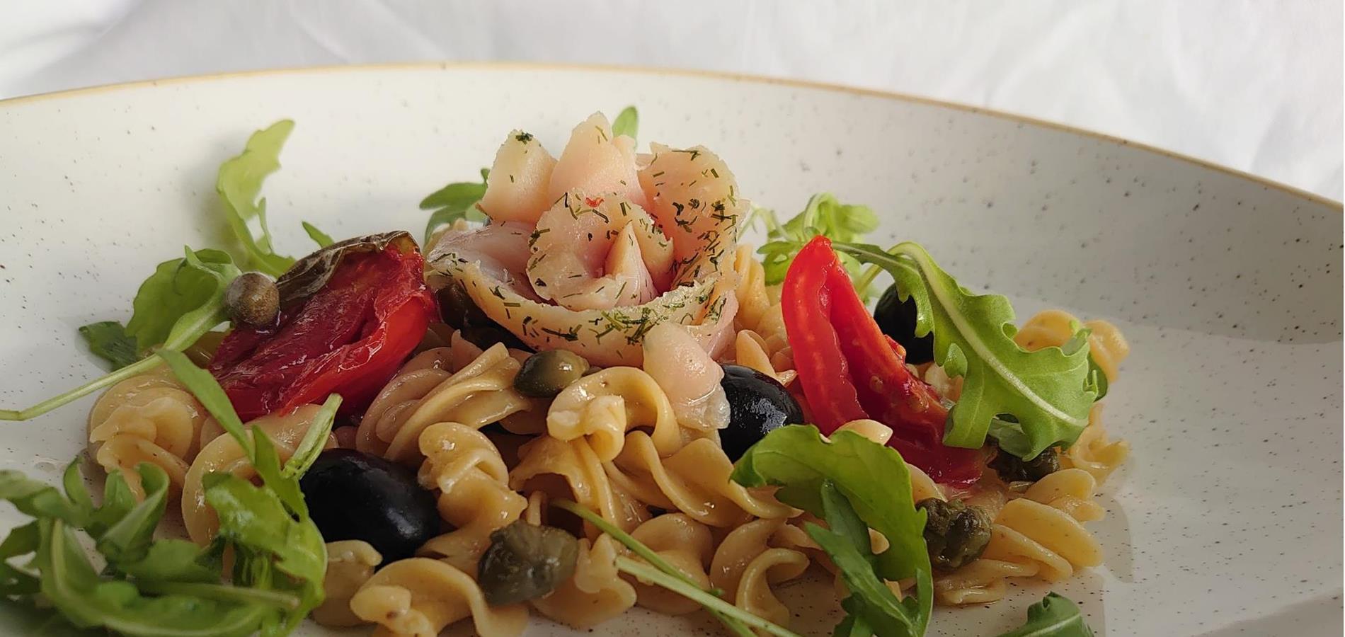 Fusilli di pan di segale con salmerino affumicato, rucola, olive, pomodori secchi e capperi