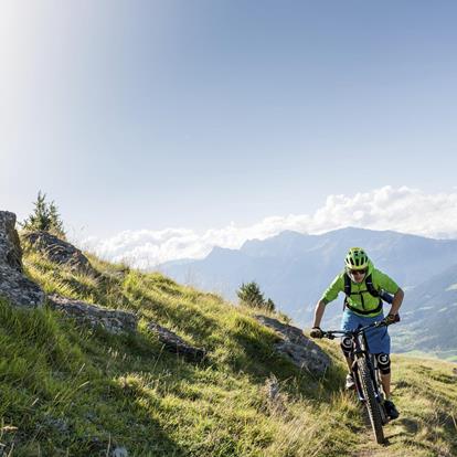 Person fährt bei schönem Wetter mit dem E-Bike den Berg hoch.