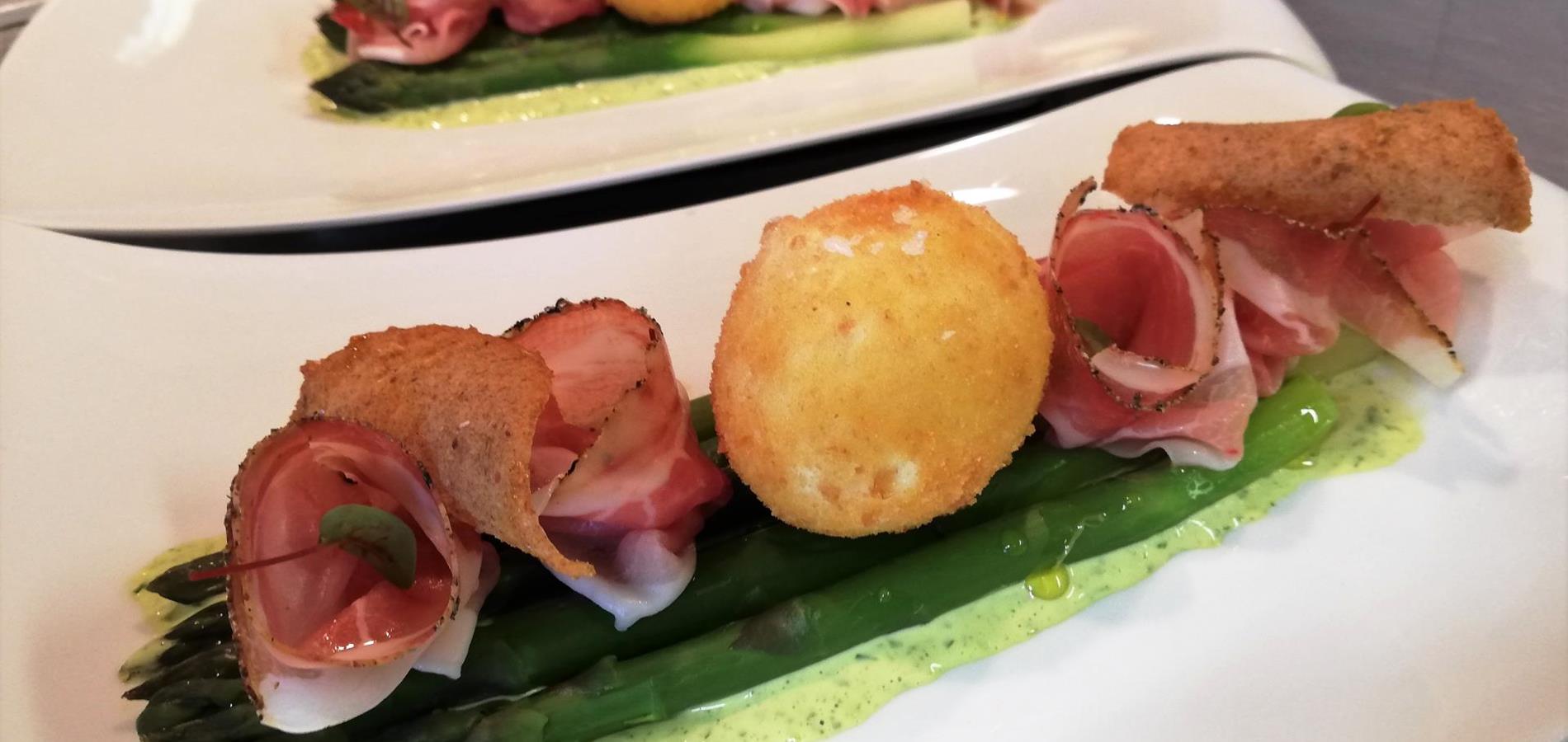 Gebackenes Freilandei und junger hausgeräucherter Speck auf grünem Spargel mit Kräutercreme