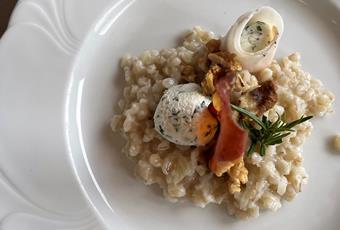 Barley risotto with herbed goat's cream cheese in a lardo coat served with bacon chips with walnuts