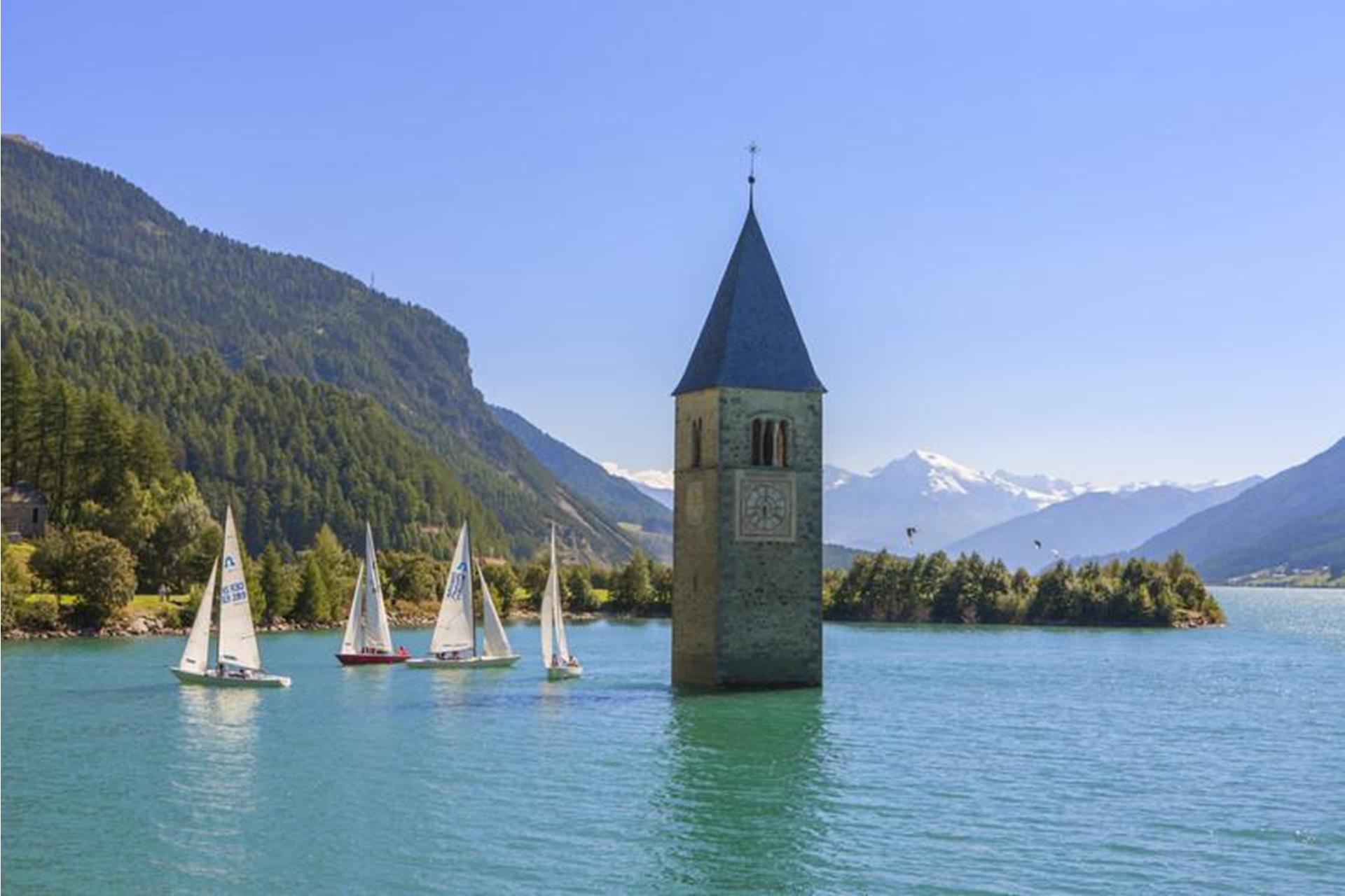 Lake Resia with submerged bell tower surrounded by sailboats