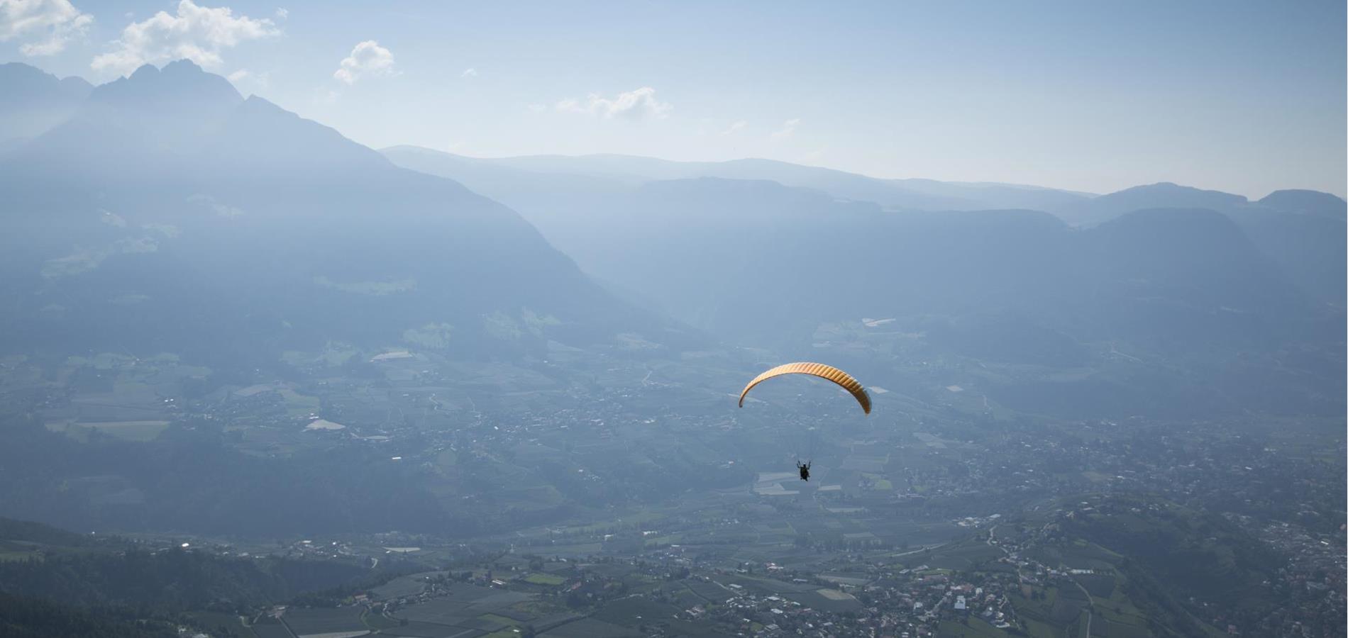 Parapendio sulle vaste distese della Valle dell'Adige in Alto Adige